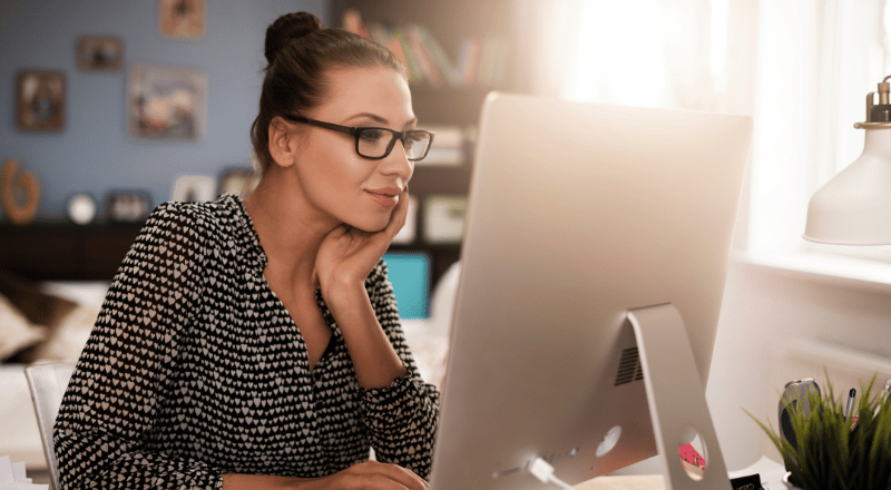 Mulher branca observando a tela de um computador enquanto procura palavras-chave para criação de conteúdo.
