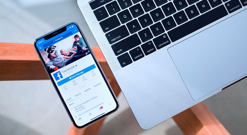 Celular ao lado de computador mostra imagem do Facebook