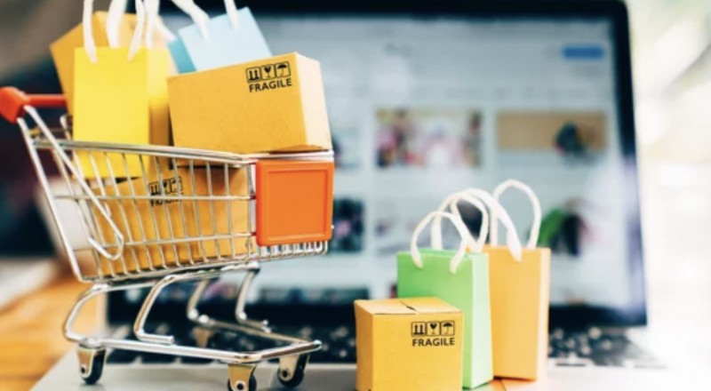 Carrinho de supermercado cjheio de sacolas e caixas.No chão também aparecem caixas e sacolas.