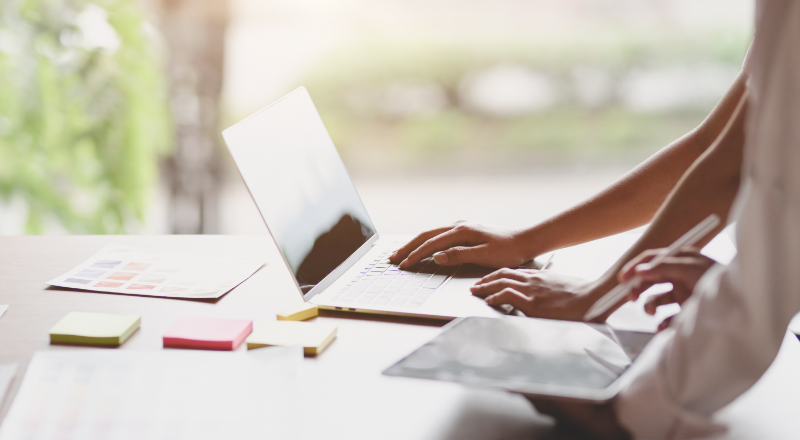 mãos femininas teclam o teclado de um notebook apoiado em uma mesa