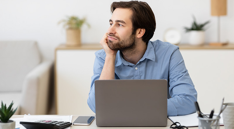 Homem branco procrastinando em frente a um notebook.