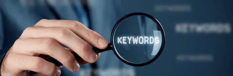 Imagem de um homem segurando uma lupa e na lente dela está escrito a palavra "Keywords"