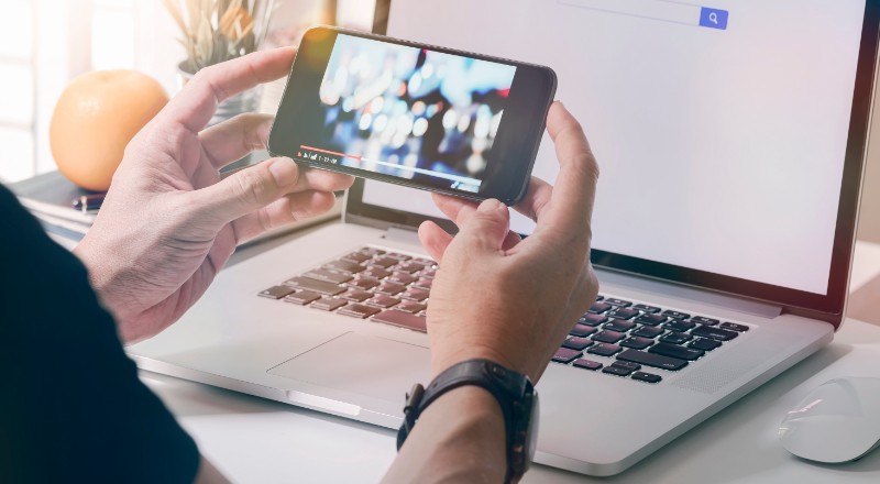 Youtube Vibes: A Webshare resume pra você os principais dados deste importante relatório Google Pessoa olhando algum geme no smartphone e notebook ao fundo