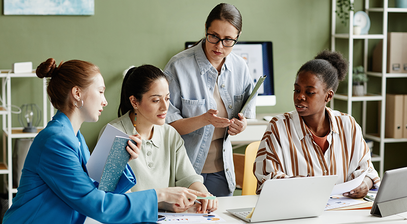 Google Bard chegou! Qual será o impacto em SEO e no marketing digital? Grupo de mulheres analisando algo em uma tela de notebook que está virada de costas para a foto.