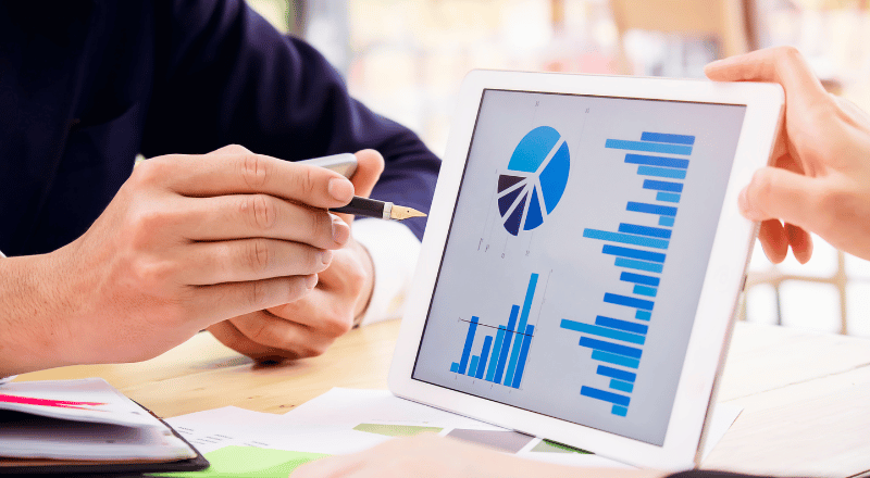 KPIs: A importância de medir e analisar os resultados do SEO Mãos apontam para uma tela de tablet com gráficos.