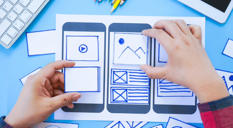 A importância de um site responsivo e otimizado Homem mexendo e motando em um celular com papel