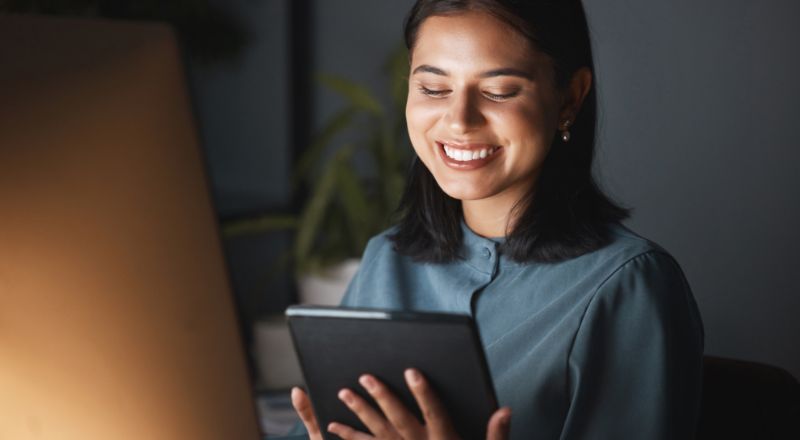 Conteúdo Criado por IA - O que o Google pensa sobre isso Mulher com mexendo no tablet e sorrindo.