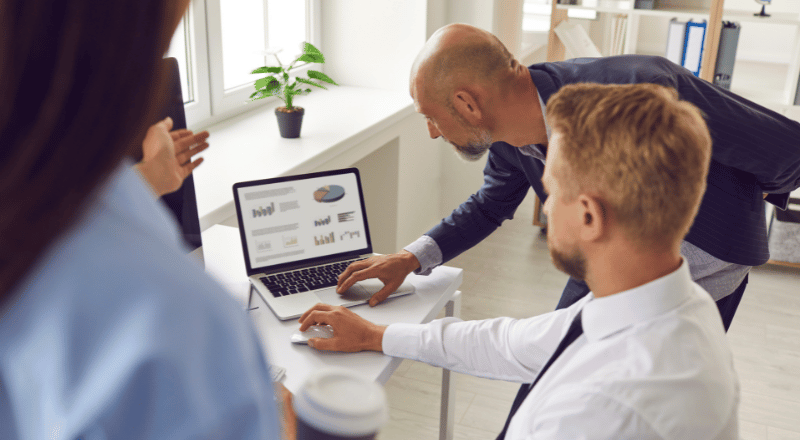KPIs: A importância de medir e analisar os resultados do SEO Três pessoas observando uma tela de notebook com gráficos.