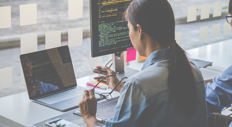 Heading tags: o que são, exemplos e como usá-las corretamente Mulher sentada observa o notebook enquanto segura um óculos com a mão esquerda e uma caenta com a mão direita.