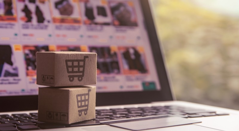 Webshare Report: Estatísticas de Maio 2022 do e-commerce no Brasil Duas caixinhas de encomendas de produtos e aofundo um notebook aberto , mostrando uma loja virtual