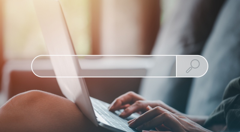 Plural x Singular - Como é melhor escrever para otimização de sites no Google? Otimização de sites: Mulher usando um notebook e um símbolo de busca por cima da foto