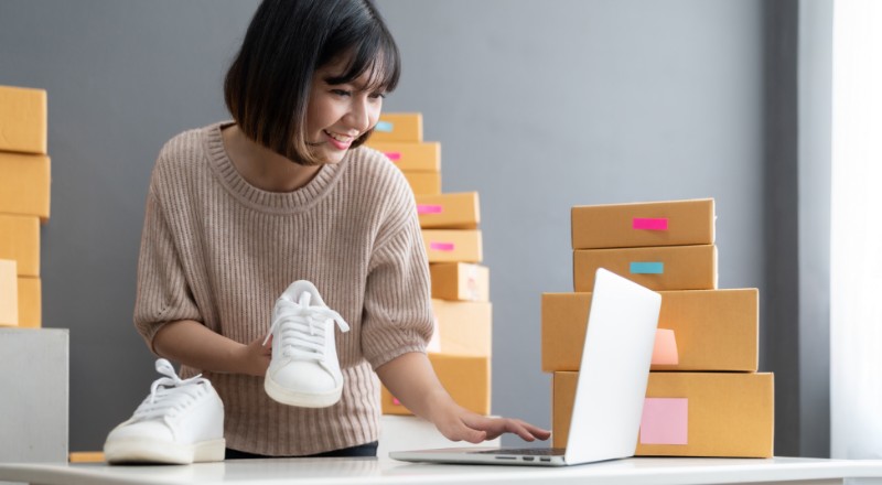 Novidade no Shopify: Eleve o SEO da sua loja com o plugin Yoast Mulher com um tênis na mão e mexendo no notebook