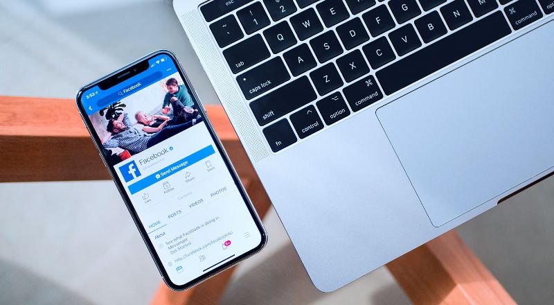 Atualizações na área: Conheça as novas ferramentas do Facebook Celular ao lado de computador mostra imagem do Facebook