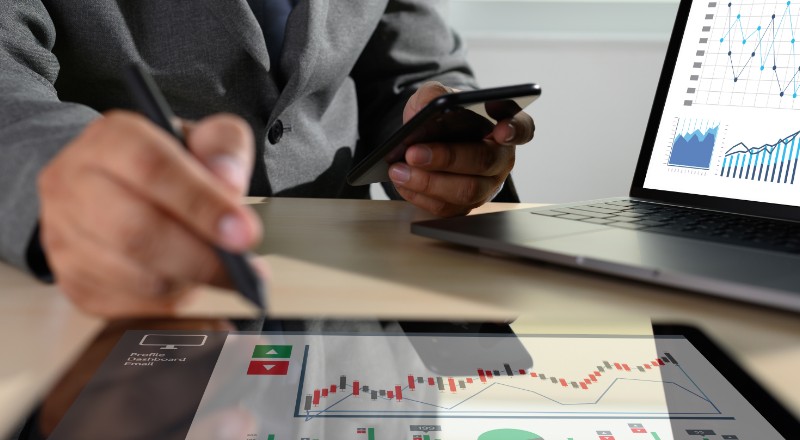 Google Search Console: o que é e como ele pode ajudar o seu site Um homem com umacenta apontando para um tablet que mostra gráficos. O mesmo homem com a outra mão segura um smartphone preto e ainda há um note book em cima da mesa.